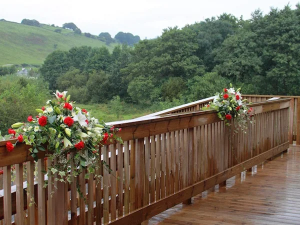 Floral arrangements displayed along the balcony railings at the Community Hall Grizebeck for a celebration.